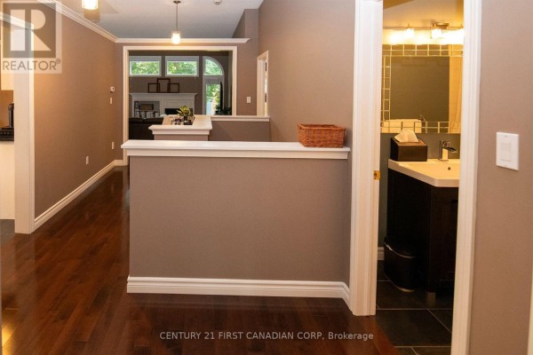 Interior hallway with a low wall, dark wood floors, and a view into a living area and bathroom. - 5 - 1100 Byron Baseline Road, London South