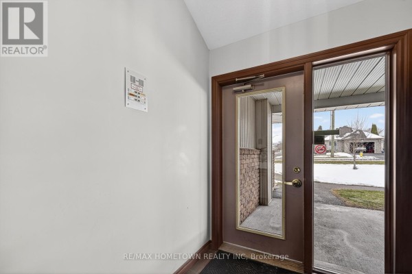 Interior view of a brown wooden front door with a mirrored glass panel. - 5 - 1171 Millwood Avenue, Brockville
