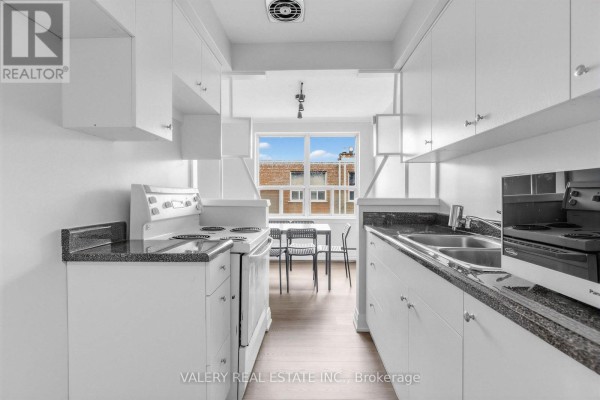 Kitchen with white cabinets, granite counters, stove, sink, and window view. - 5 - 12 Westgate Boulevard, Toronto