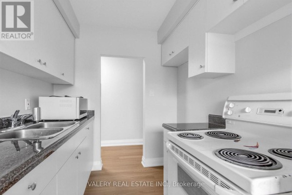 Kitchen with white cabinets, granite counters, stove, and sink. - 5 - 12 Westgate Boulevard, Toronto