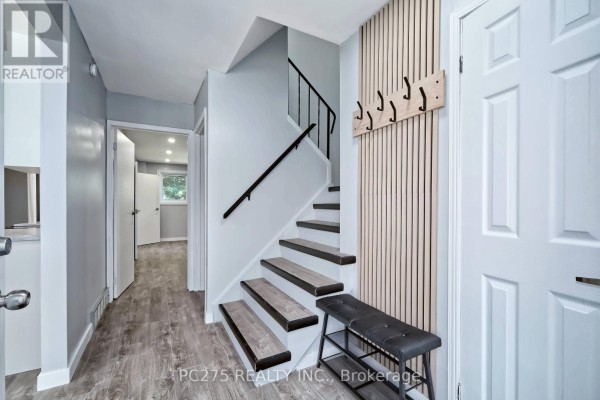 Interior foyer with light grey walls, wood-look flooring, stairs, and a bench. - 5 - 1460 Limberlost Road, London North