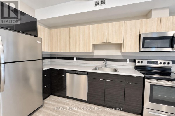 Modern kitchen with stainless steel appliances, light wood upper cabinets, dark lower cabinets, and a grey backsplash. - 5 - 147 Pond Mills Road S, London South