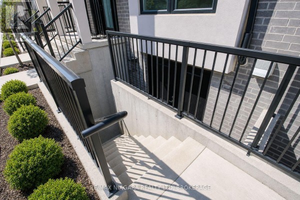 Concrete stairs with black railings leading down to a basement entrance. - 153 Summersides Boulevard, Pelham