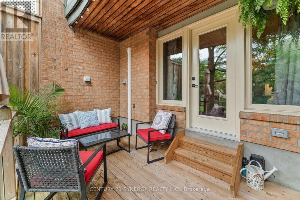 Covered wooden deck with outdoor seating and patio doors leading inside. - 5 - 2 Columbus Avenue, Ottawa