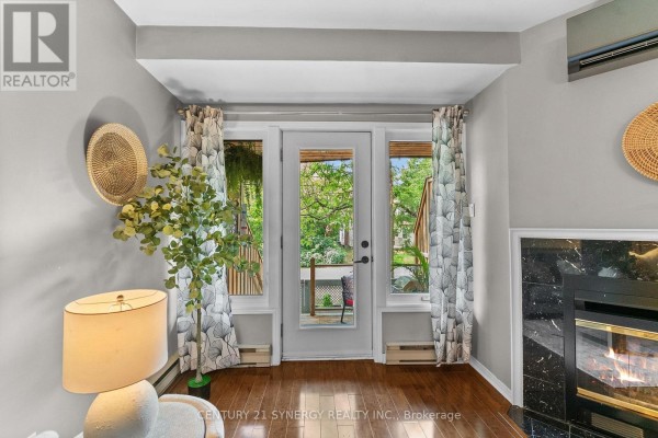 Living room with a fireplace, large windows, and a glass door to a patio. - 5 - 2 Columbus Avenue, Ottawa