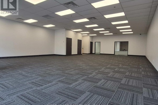 Wide view of an empty commercial space with grey patterned carpet and bright fluorescent lighting throughout. - 5 - 20 Steelcase Road W, Markham