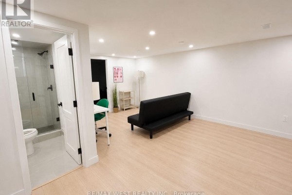 View of the basement from the doorway, showing a living area, desk, and an open bathroom. - 5 - 202 Perth Avenue, Toronto