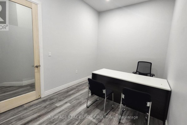 Office with a desk, chairs, and a glass-paneled wooden door leading to a mirrored hallway. - 5 - 204 - 15 Brownridge Road, Halton Hills