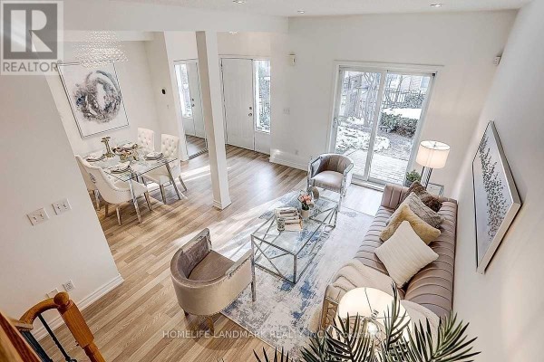 High-angle view of an open-concept living and dining area with light wood floors and glass doors leading outdoors. - 5 - 21 St Moritz Way, Markham