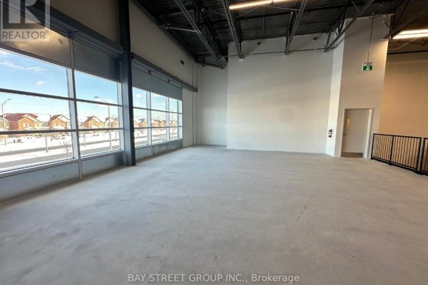 Empty commercial space with concrete floor, white walls, and large windows overlooking houses and a street. - 5 - 2560 Morningside Avenue, Toronto