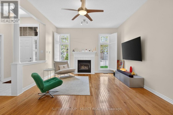Living room with hardwood floors, a gas fireplace, a green chair, and a television. - 5 - 270 North Centre Road, London North
