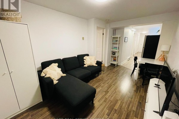 Living room with a black sectional sofa, white furniture, and an adjacent hallway with a desk. - 5 - 296 Runnymede Road, Toronto