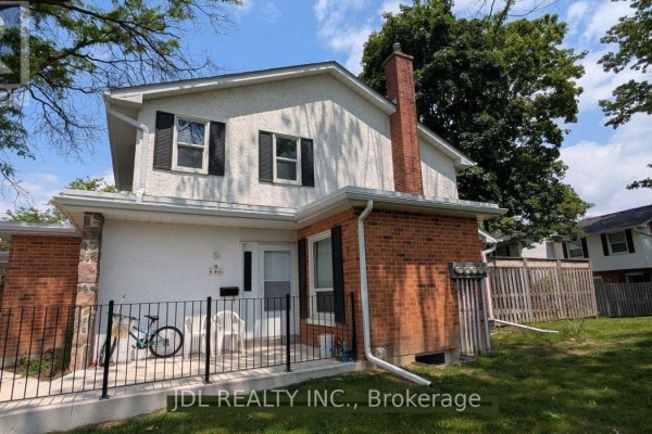 Exterior view of townhouse with white stucco and brick facade, front door, and fenced patio. - 5 - 431 Keats Way, Waterloo