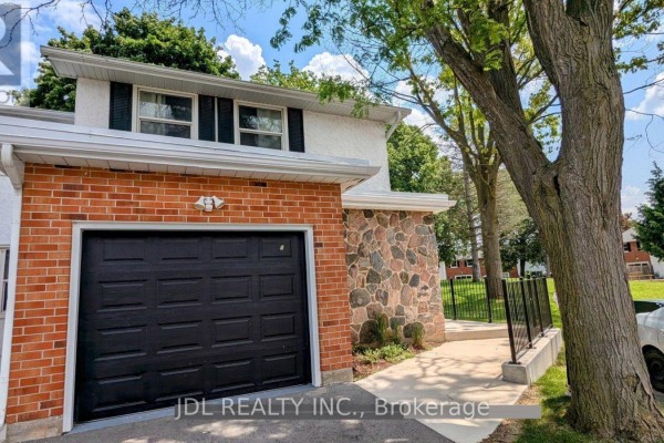 Front exterior of townhouse featuring a black garage door, brick and stone accents, and driveway. - 5 - 431 Keats Way, Waterloo