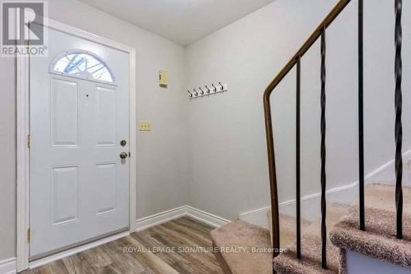 Interior entryway with a white door, light grey walls, and a carpeted staircase. - 5 - 46 Mountainview Road S, Halton Hills