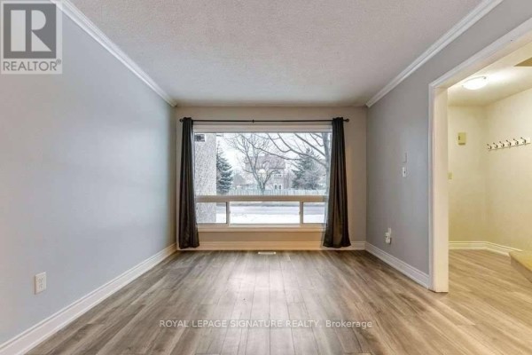 Living room with a large window overlooking the street, grey walls, and wood-look flooring. - 5 - 46 Mountainview Road S, Halton Hills