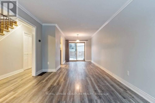 Living and dining area with light grey walls, wood-look flooring, and a sliding glass door. - 5 - 46 Mountainview Road S, Halton Hills