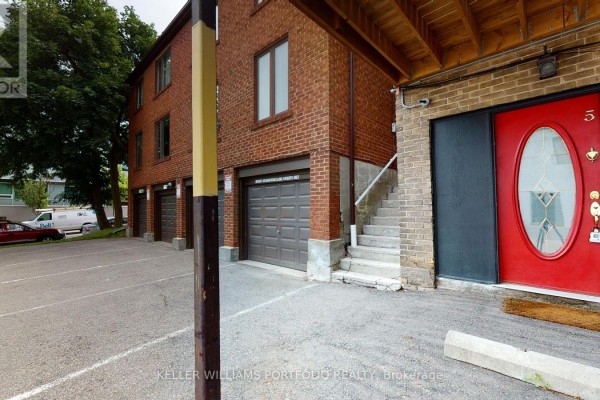 Side view of brick building with garages, exterior stairs, and red front door. - 5 - 546 Eglinton Avenue E, Toronto