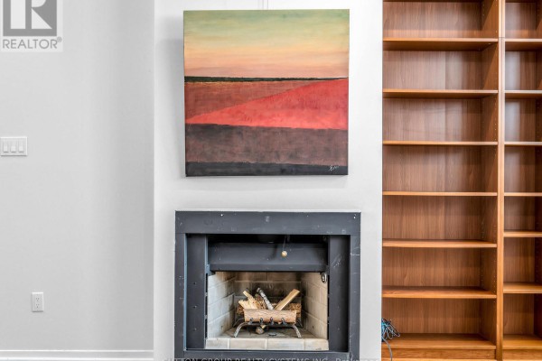Spacious living area with hardwood floors, brick accent wall, built-in shelving, white cabinets, and fireplace. - 5 - 6 Bartlett Avenue W, Toronto