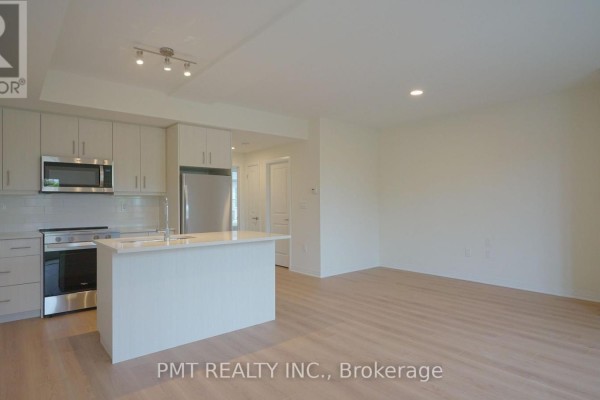 Kitchen area with white island, stainless steel appliances, and light wood floors. - 5 - 737 Front Royal Street, Mississauga