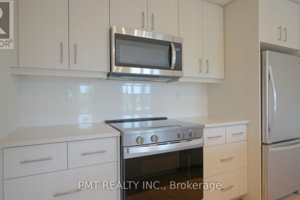 Close-up of stainless steel microwave above a stainless steel stove and white cabinetry. - 5 - 737 Front Royal Street, Mississauga