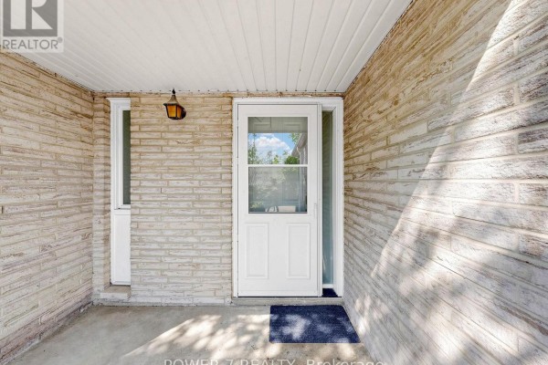 Front entrance of a townhouse with a white door, brick wall, and a porch light. - 5 - 77 Rameau Drive, Toronto
