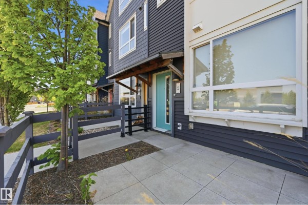 Patio area in front of a townhouse with a teal door and grey fence. - #5 100 Jensen Lakes Bv, St  Albert