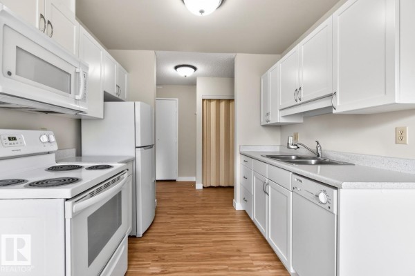 U-shaped kitchen with white cabinets, white appliances, stainless steel sink, and wood laminate flooring. - #5 11265 31 Av Nw, Edmonton
