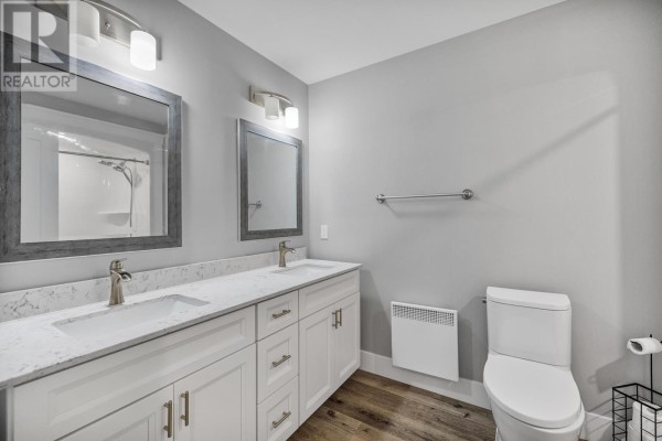 Double vanity bathroom with white countertops, two sinks, and silver fixtures, next to a toilet. - 5 12 Harold Court, Cornwall