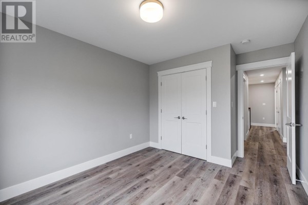 Empty room with light grey walls, double closet doors, and light wood laminate flooring. - 5 12 Harold Court, Cornwall
