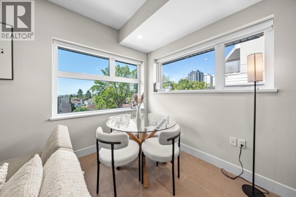 Small dining nook with glass table, white chairs, and large windows. - 5 128 W Woodstock Avenue, Vancouver