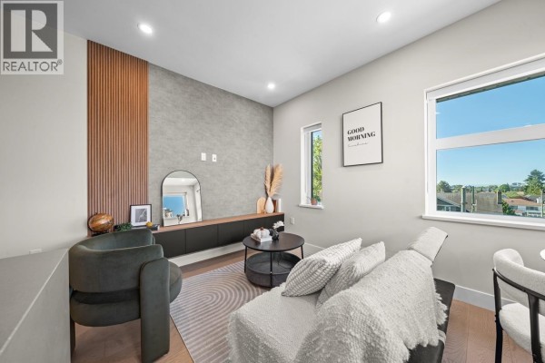 Living room with couch, armchair, modern entertainment unit, and large windows. - 5 128 W Woodstock Avenue, Vancouver