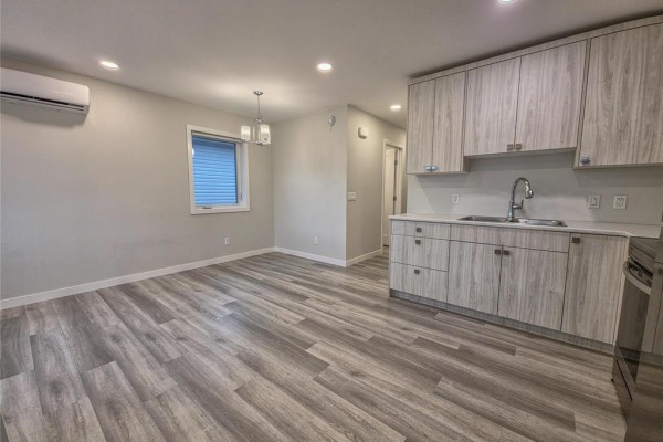 Open concept living and kitchen area with light wood cabinets, white countertops and stainless steel appliances. - 5 235 Glen Avenue, Brandon