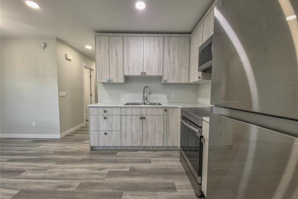 Kitchen with stainless steel refrigerator, light wood cabinets, white countertops, and a black stovetop. - 5 235 Glen Avenue, Brandon