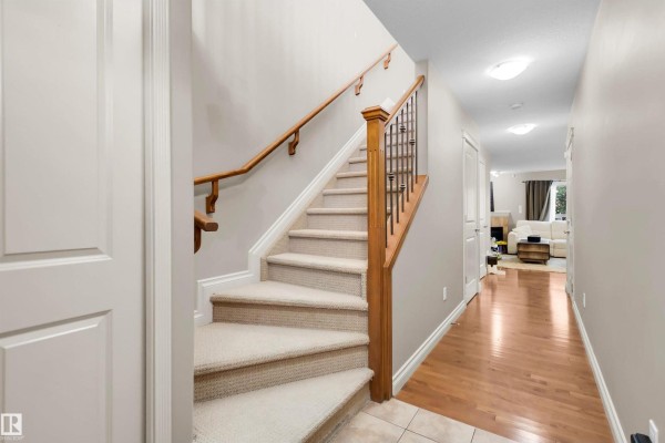 Interior hallway with tiled floor and carpeted stairs with wood banister. - #5 5120 164 Av Nw, Edmonton