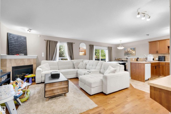 Living room with white sectional couch, fireplace, and wood floors. - #5 5120 164 Av Nw, Edmonton