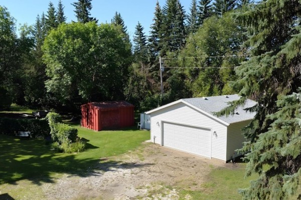 White detached garage and a red shed in a grassy yard surrounded by trees. - #5 54015 Rge Road 262, Rural Sturgeon County