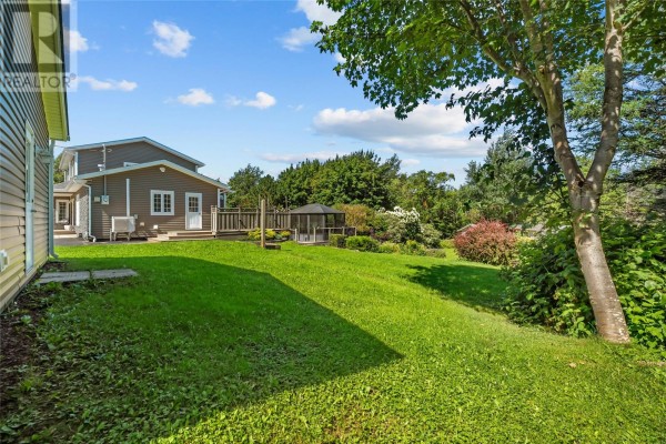 Backyard with a green lawn, deck, gazebo, and lush landscaping. - 5-7 Spelling Hill Road, Burin Bay Arm