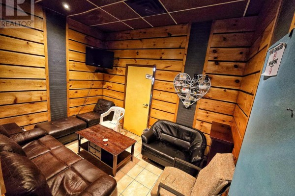 A wood-paneled room with leather sofas, a coffee table, and a mounted television. - 5-8 - 9688 Leslie Street, Richmond Hill