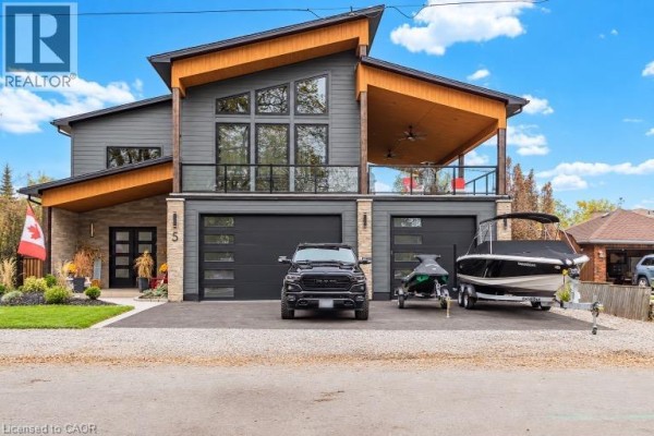 Modern house exterior with two garages, boat, jet ski, and truck parked in driveway. - 5 Archibald Drive, Port Rowan