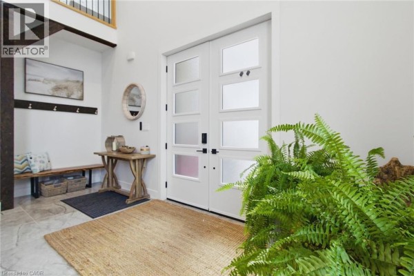 Interior foyer with double white doors, console table, bench, and large potted plant. - 5 Archibald Drive, Port Rowan