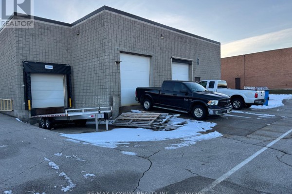 Loading area with two trucks, trailer, and stacked pallets against building - 5 Automatic Road, Brampton