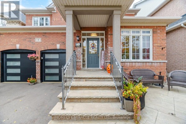Close-up of the front porch of a brick house, featuring a dark teal door and seating. - 5 Billancourt Crescent, Brampton