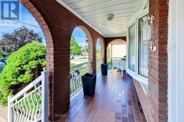 Covered porch with brick pillars, tiled floor, white railing, and decorative planters. - 5 Byworth Boulevard, Toronto