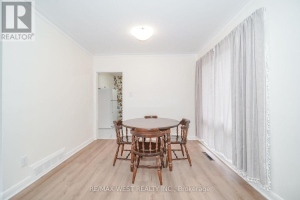Dining area with a wooden table and four chairs near a large window with sheer curtains. - 5 Cromarty Drive, Toronto