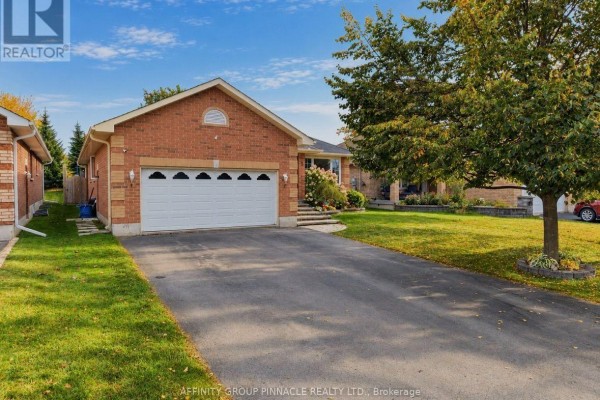 Side view of a brick bungalow with a long driveway and green lawn. - 5 Denfield Road, Kawartha Lakes