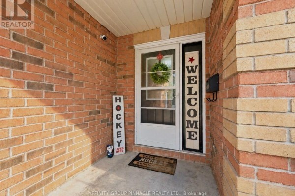 Entranceway of a brick house with a white door, welcome signs, and a wreath. - 5 Denfield Road, Kawartha Lakes