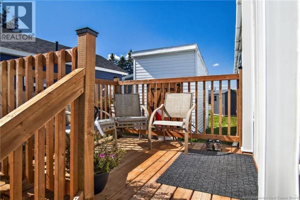 Close-up of a wooden deck with two chairs and a small table, with a gray welcome mat. - 5 Dove Street, Saint John