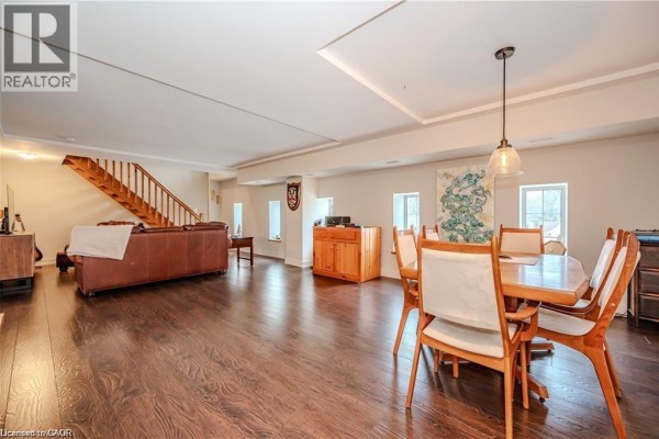 Open-concept living and dining area with dark hardwood floors and a wooden staircase. - 5 Father David Bauer Drive Unit# 301, Waterloo