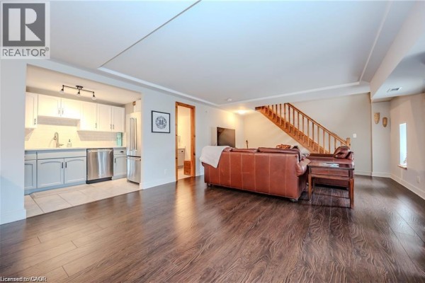 Living room area featuring a leather sofa and a view towards the kitchen and stairs. - 5 Father David Bauer Drive Unit# 301, Waterloo